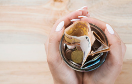 woman s hand holding glass jar with euro notes coins wooden backdrop